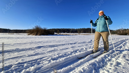 Mature woman skiing on trail in winter cold weather. Cross-country skier in snowy National park Sumava, Czech Republic.