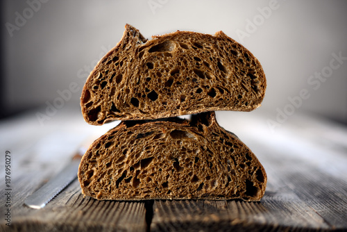 Two fresh half of rye sourdough bread in section on a rustic wooden board. Artisan farmhouse-style loaf captured in warm natural lighting