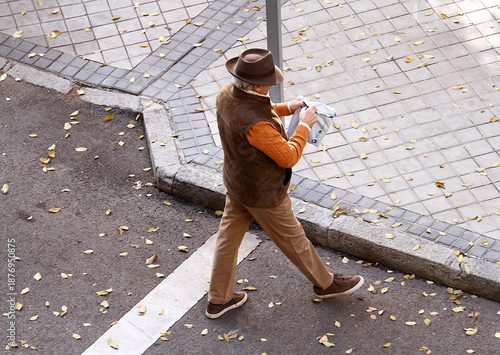 Fotografie Señor elegante con clase, estilo, sombrero y chaleco cruzando calle y abriendo p