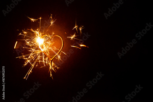 Cierge magique motif coeur avec des étincelles dorées scintillantes sur un fond brun foncé, fête de la Saint Valentin, ambiance chaude