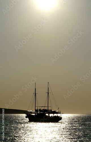 Silhouette of tour boat with happy tourist on it at golden hour in light yellow color tone
