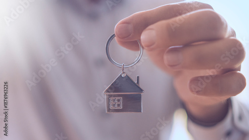 Housing affordability crisis and rising real estate market prices concept Person holding a house-shaped keychain, symbolizing the selling and purchasing real estate home.