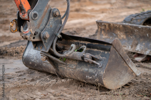 Bucket of a mini excavator during earthworks on a construction site. Concept of construction, mechanized labor, and use of specialized machinery.