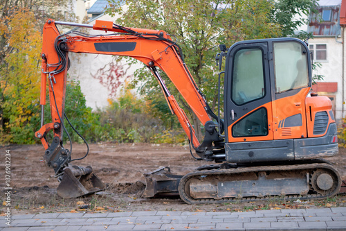 Mini excavator working on a construction site during earthworks. Concept of construction, infrastructure development, site preparation, and use of heavy machinery.