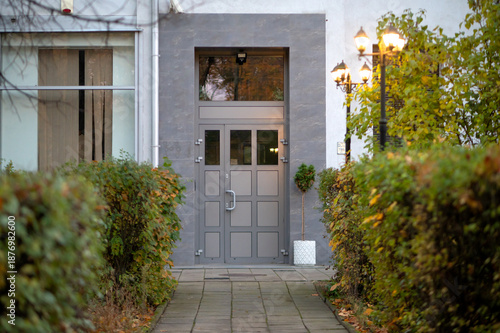 Entrance to a modern apartment building with classic street lamps. Illuminated residential area, comfort and safety concept, urban real estate, housing and property investment background.