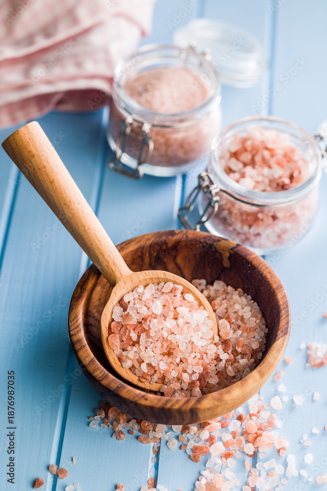 Fototapeta premium Pink Himalayan salt on wooden spoon on blue table.
