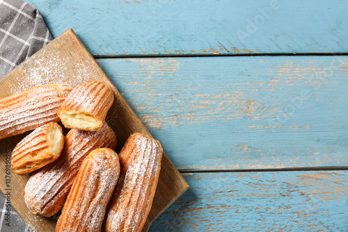 Board with tasty eclairs on...
