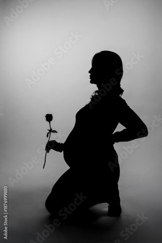 silhouette of a pregnant woman holding a rose in her hand