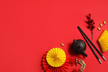Teapot with tree branch, chopsticks and Chinese symbols on red background