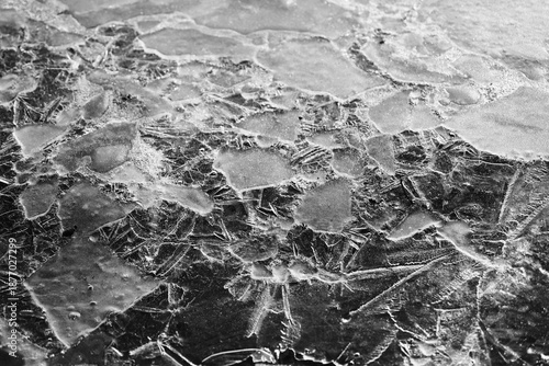 Cracked natural ice surface with frozen patterns and fractures, abstract winter texture background symbolizing cold, climate and fragile nature.