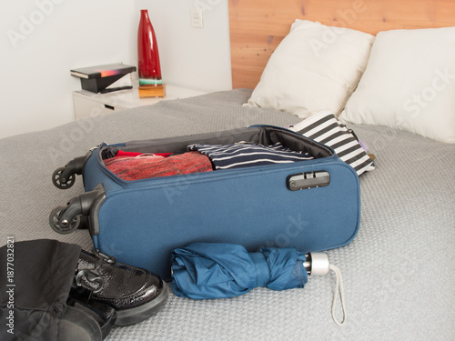Packing for a weekend. Small travel suitcase on bed