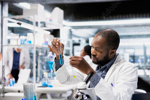 Fotografi Clinical lab technician analyzes blue liquid chemical sample properties in glass test tube