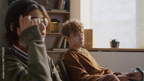 Distressed teenage girl taking in couple therapy holding grudge against resentful boyfriend giving partner side eye glance during conversation in counselling office