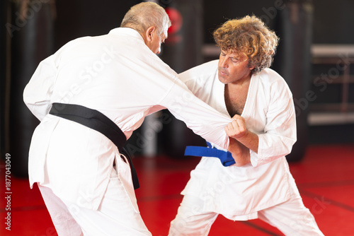 Bild auf Leinwand Concentrated blue-belt middle-aged aikido fighter in white gi honing fighting te