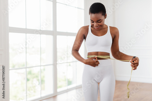 Weight Loss Concept. Portrait of smiling fit African American lady measuring her waist looking at yellow tape, blurred background. Slim black woman happy with her body. Healthy lifestyle, free space Free Download Weight Loss Concept. Portrait of smiling fit African American lady measuring her waist looking at yellow tape, blurred background. Slim black woman happy with her body. Healthy lifestyle, free space - GFXLoad