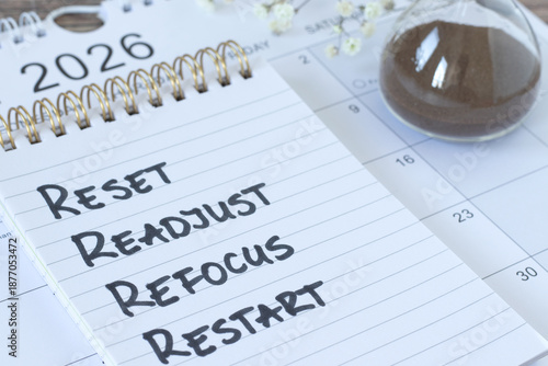 Reset, readjust, refocus, restart, inspirational checklist text in notebook with January 2026 calendar and hourglass. Time management, goals, success, and aspirations concept.