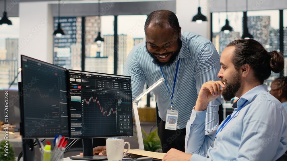 Fototapeta premium Happy coworkers in office doing high five after successful trading strategy on stock market. Joyous teamworking traders at PC desk celebrating, delighted about investment profits
