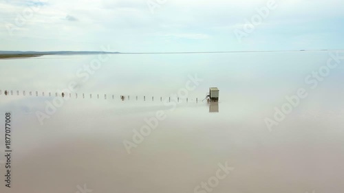 Abandoned wooden structure standing isolated in the pink waters of Tuz salt lake in Turkey