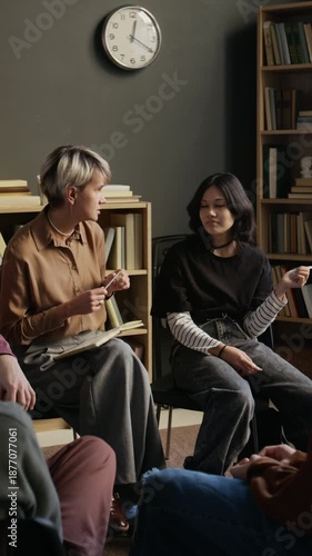 Vertical shot of female psychotherapist talking to guarded teenage girl with black hair during shared discussion in therapy room