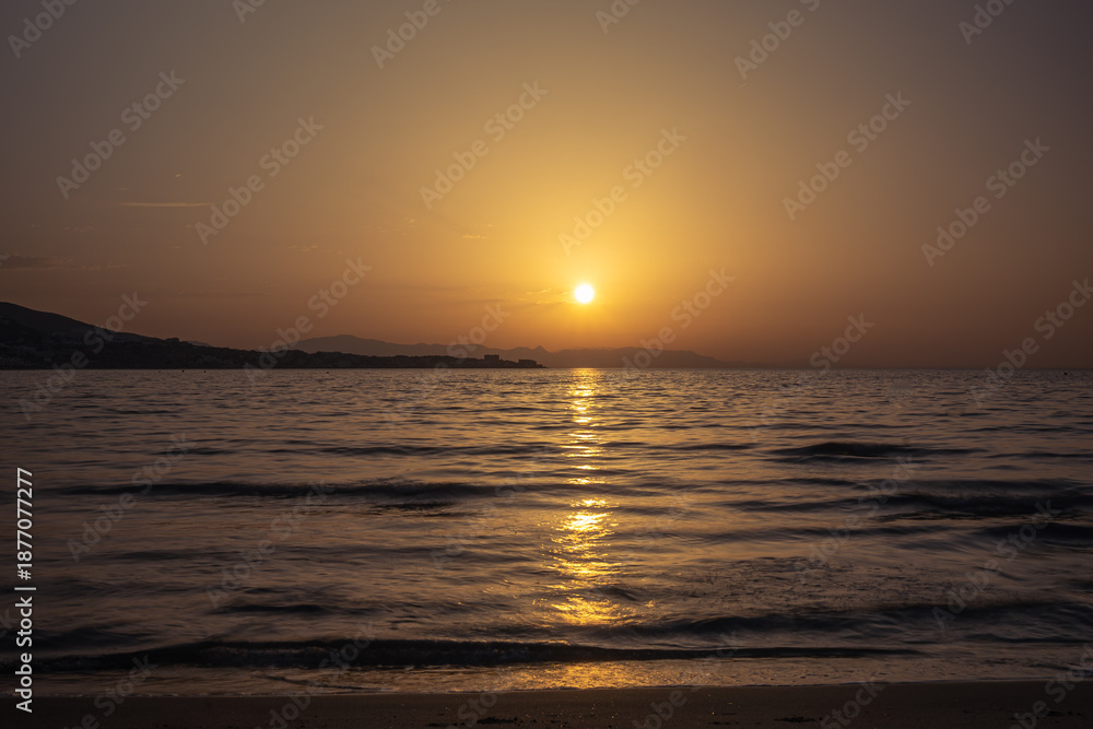 Obraz premium Golden sunset reflection on the calm sea surface.