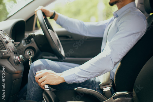 Photos Unrecognizable businessman with fasten seat belt driving new comfy auto, holding hands on gear and steering wheel, side view