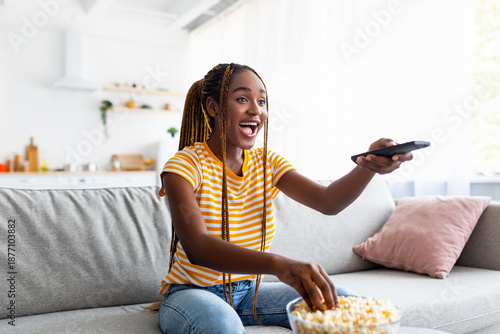 Φωτογραφία Laughing afro american young pretty woman with long braids sitting on couch, eat