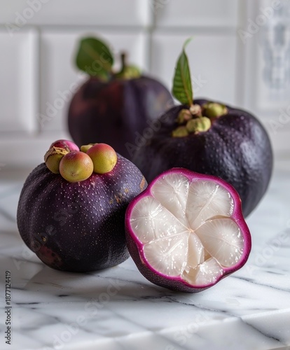 Fresh mangosteen fruit with deep purple skin and white flesh on marble surface