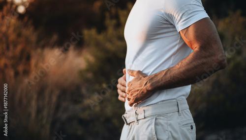 Man holding his waist in pain outdoors during daytime
