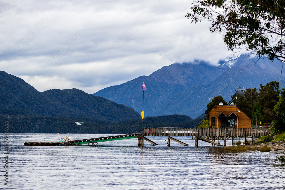 Fototapeta premium Jetty and Lakeside Hut on Lake Te Anau with Fiordland Mountains, New Zealand