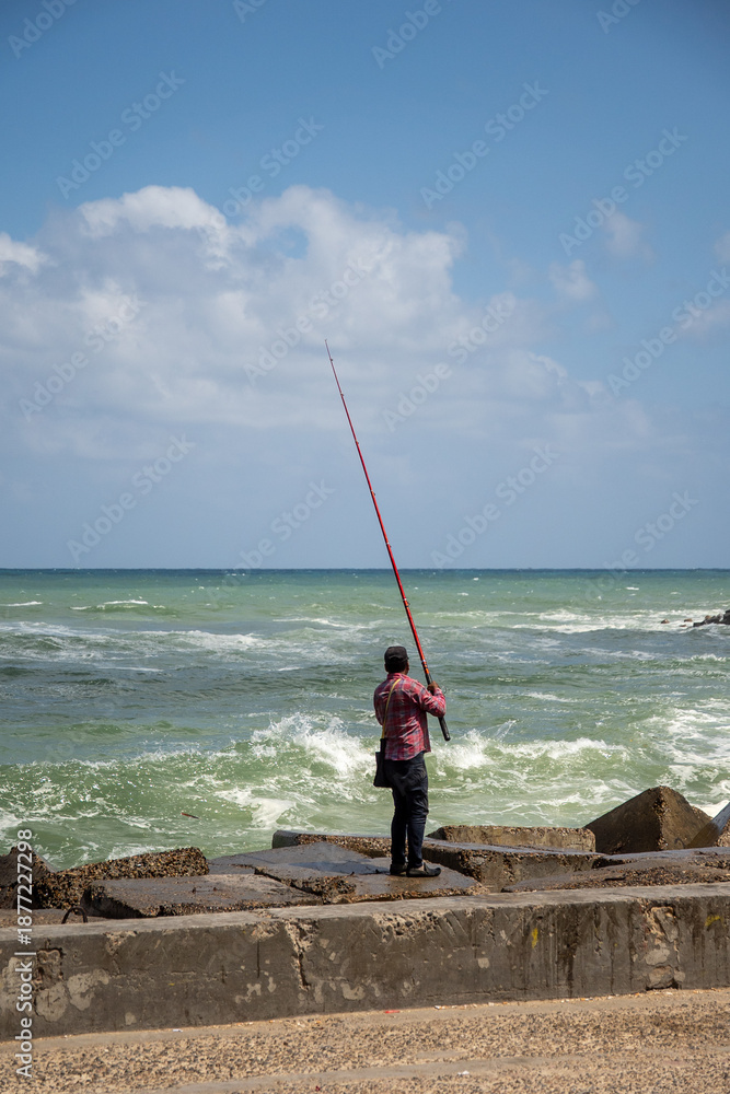Fototapeta premium Man fishing from a jetty in Alexandria, Egypt