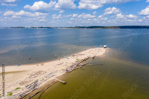 Aerial view of the sandy spit of an uninhabited island and a city with tall buildings on the horizon