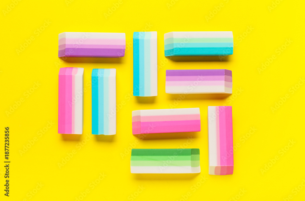 Fototapeta premium Many colorful rubber erasers on yellow background