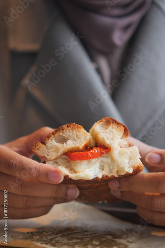 Quadro su tela Person holds sandwich with tomato and cream at restaurant