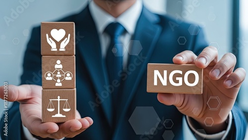 Businessman holding NGO blocks with social icons for non-profit organization