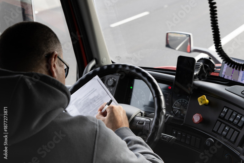Driver reviews documents while operating truck on highway in Pleasant Grove California