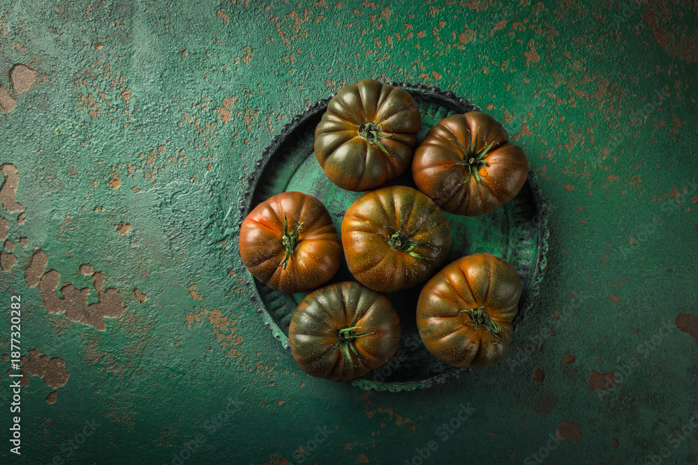 Obraz premium Large black tomato on a green vintage background