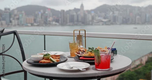 Appetizing quesadillas, nachos, and vibrant cocktails served on a stylish outdoor table, enjoying a luxurious meal with a panoramic view of a vibrant city skyline and harbor. Upscale dining, urban