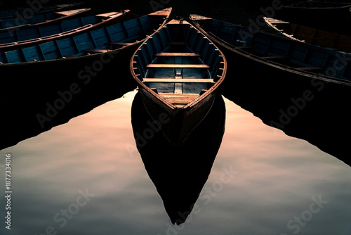 Fotografi A symmetrical composition of traditional wooden rowboats floating on still water, creating a mirror-like reflection