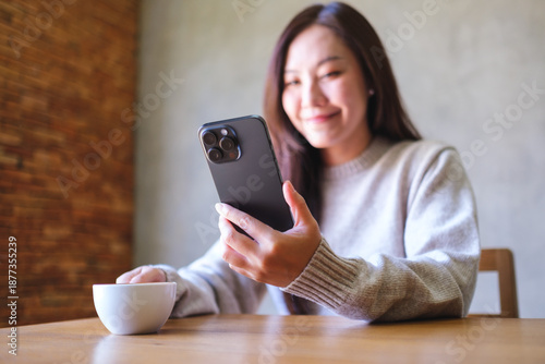 Wallpaper Mural Portrait image of a woman holding and using mobile phone while drinking coffee in cafe Torontodigital.ca