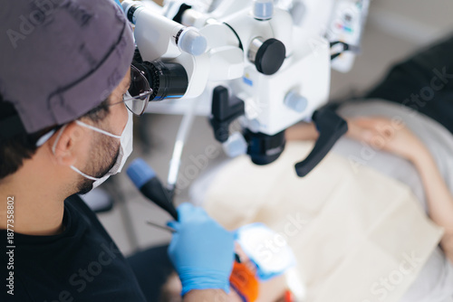 Tableau sur toile Male surgeon performing microsurgery in medical clinic with microscope