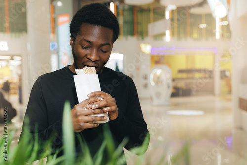 Photography Portrait Young african male enjoying doner fast food in modern shopping mall