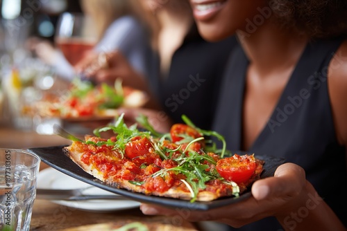 Hand Holding Tomato and Arugula Pizza Slice Close-Up for Restaurant Dining and Social Scene
