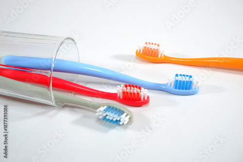 Vibrant toothbrushes in red, orange, blue, and grey arranged on white background, evoking a sense of cleanliness and oral health, Daily routine concept photography
