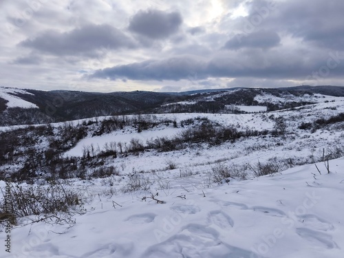 Snowy Hills and Frozen Valley Under Dramatic Winter Sky