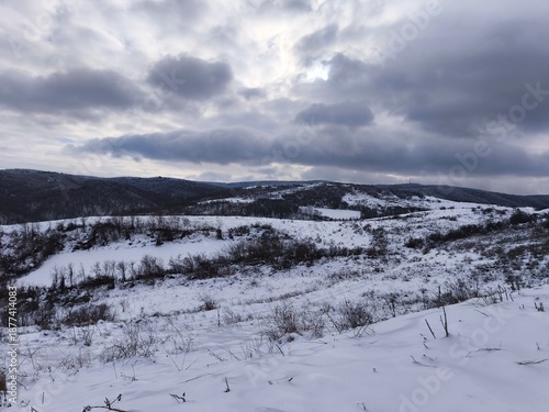 Snowy Hills and Frozen Valley Under Dramatic Winter Sky