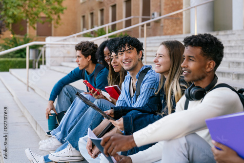 Quadro su tela Group of diverse university students sitting on campus stairs, interacting and e