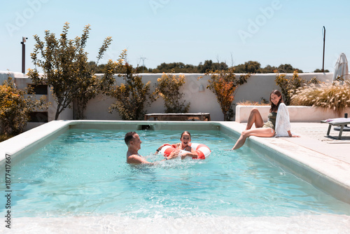 Family enjoying summer vacation swimming in backyard pool