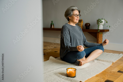 Senior woman meditating at home creating zen atmosphere