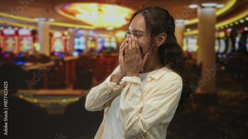 Quadro em tela Woman laughing with hands covering mouth at slot machine in casino building; surprise winning moment