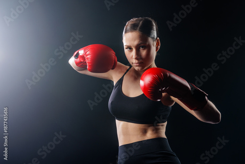 Valokuva Female boxer in red gloves ready to punch in studio on dark background